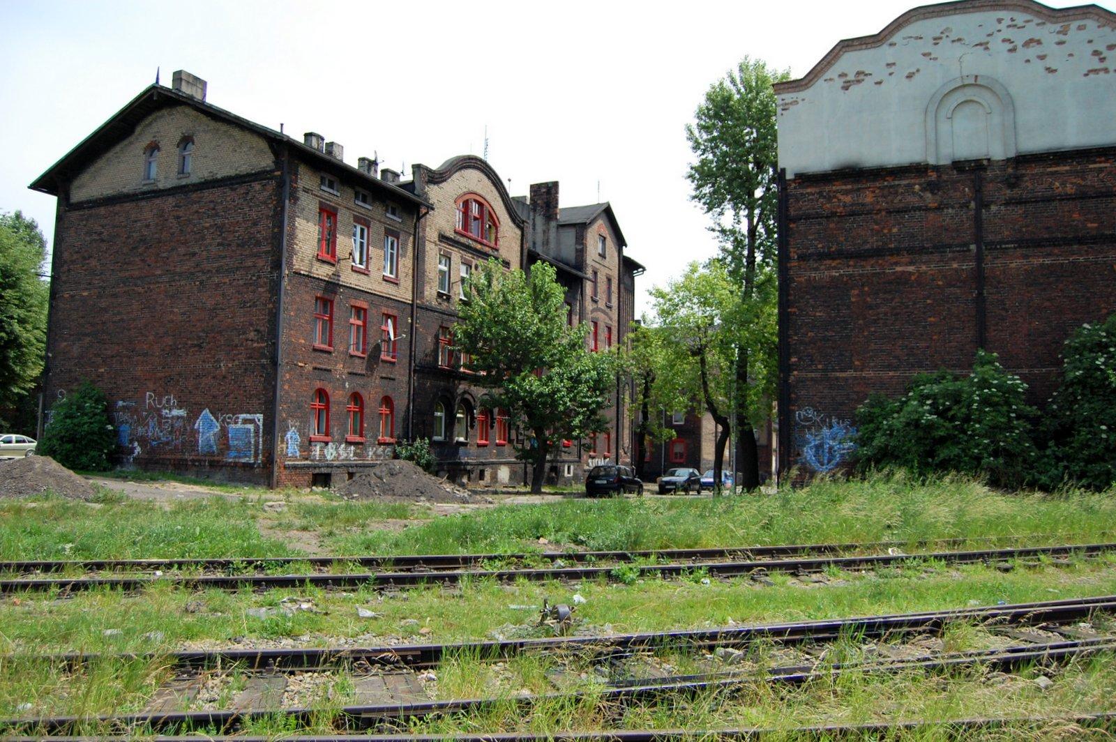 Tory kolejowe obok domów z czerwonej cegły