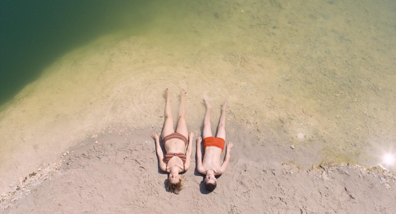 Kobieta i mężczyzna leżący na piasku nad wodą