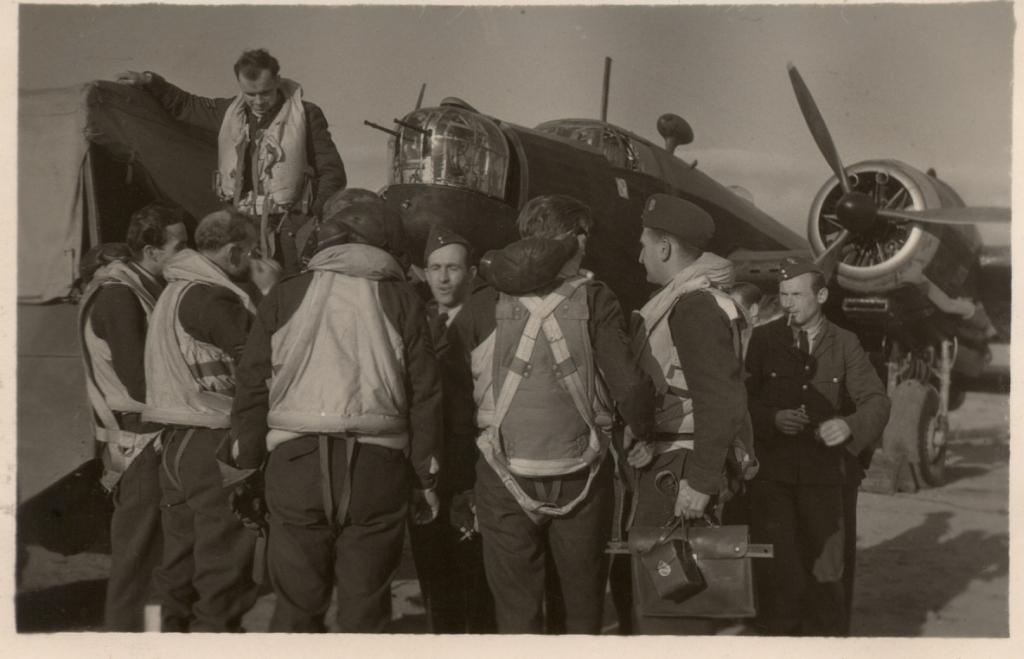 Czarno białe zdjęcie mężczyzn stojących na tle samolotu