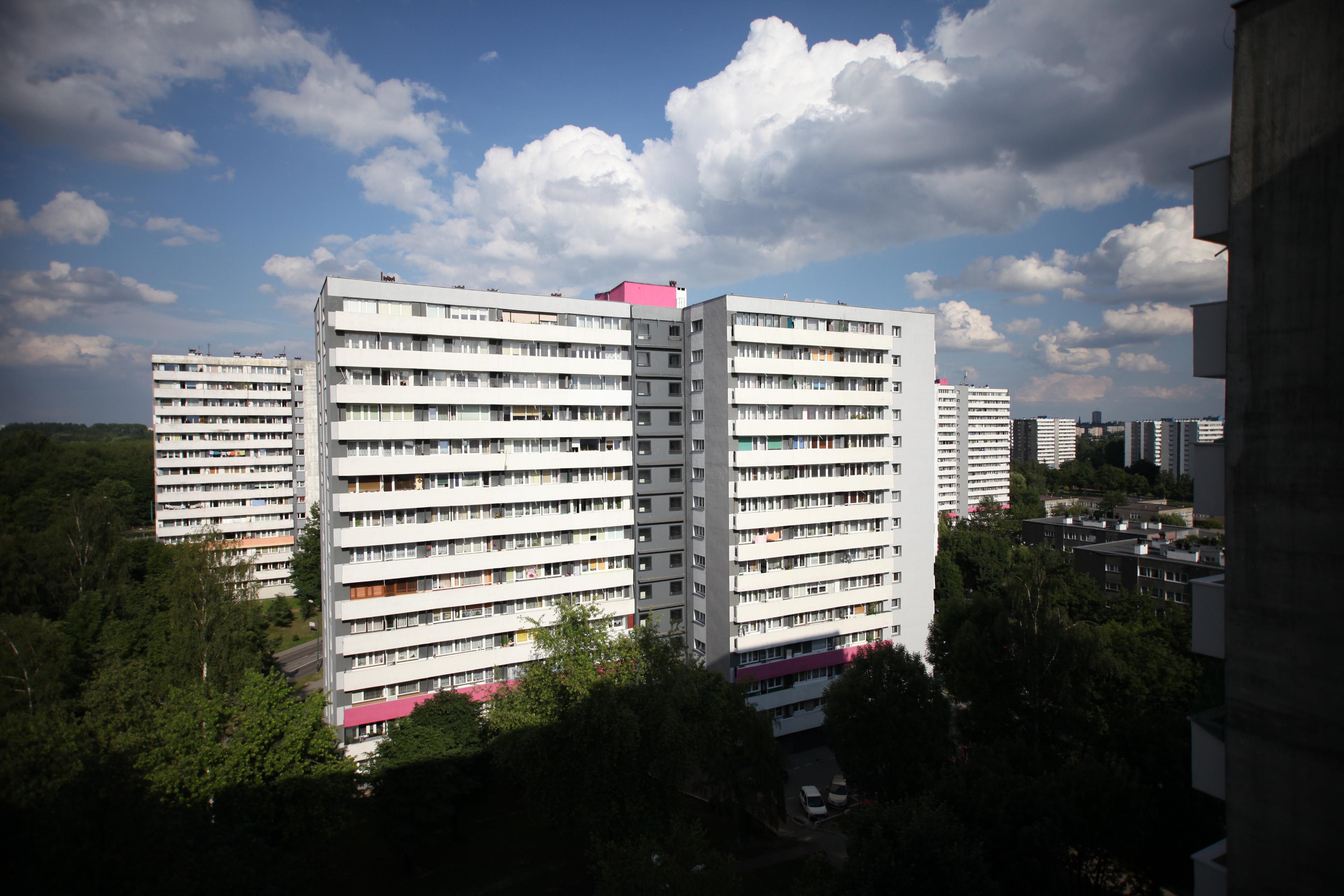 Kilku piętrowy blok w otoczeniu drzew