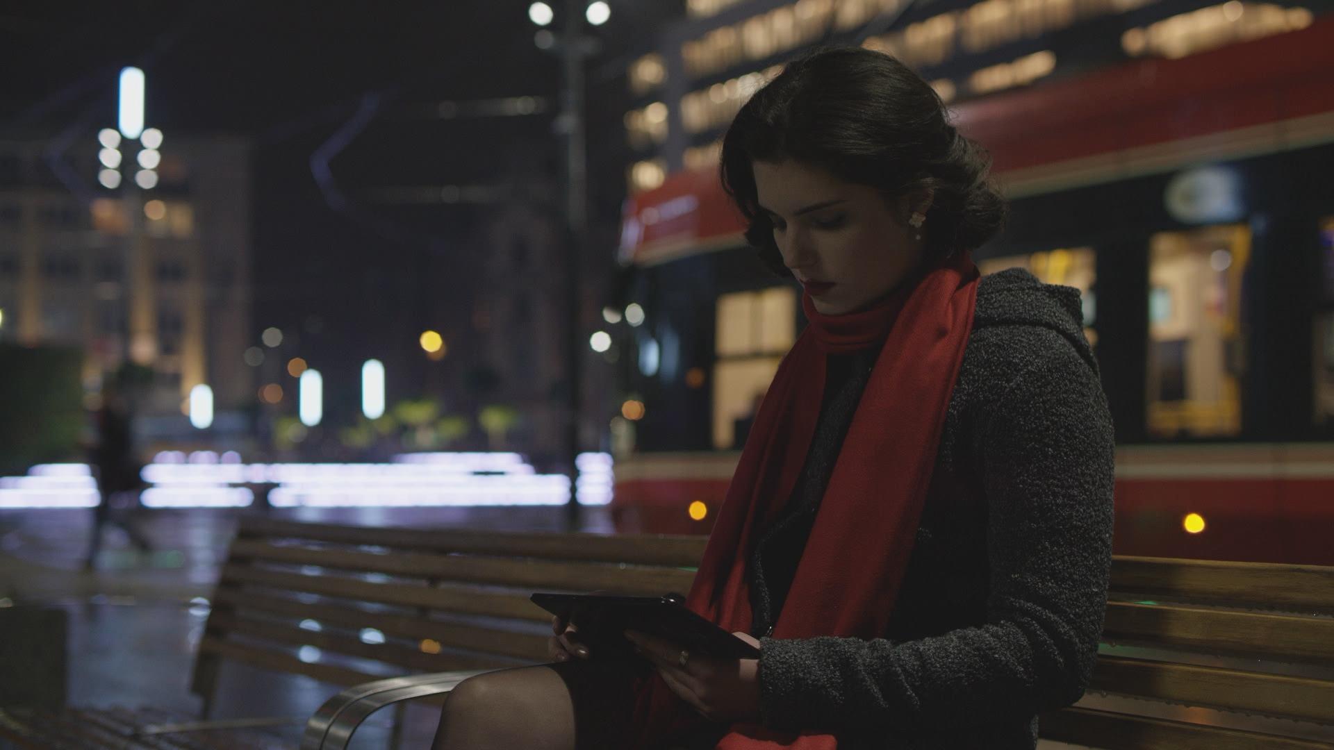 Kobieta siedząca na ławce na tle tramwaju